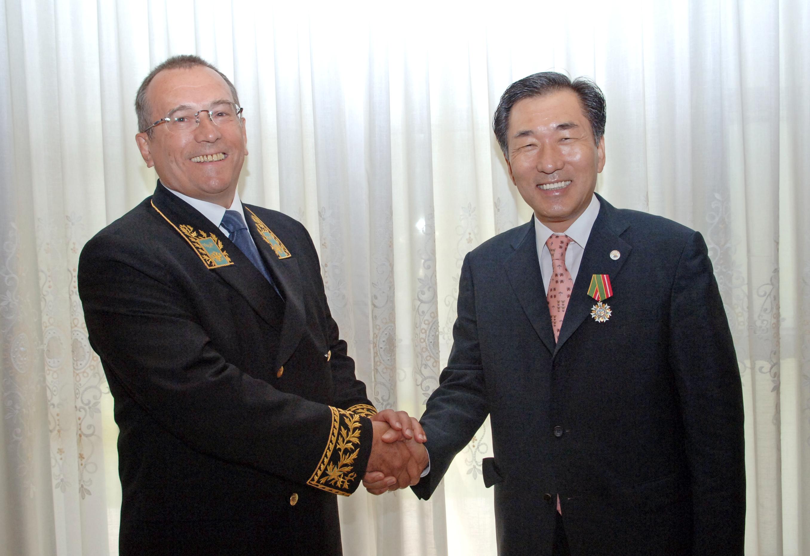 안상수 시장이휘장을 전수 받고 이반센초프 러시아 대사와 악수를 나누고 있다